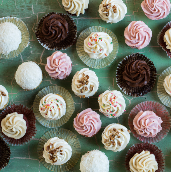 A variety of cupcakes arranged on a green countertop