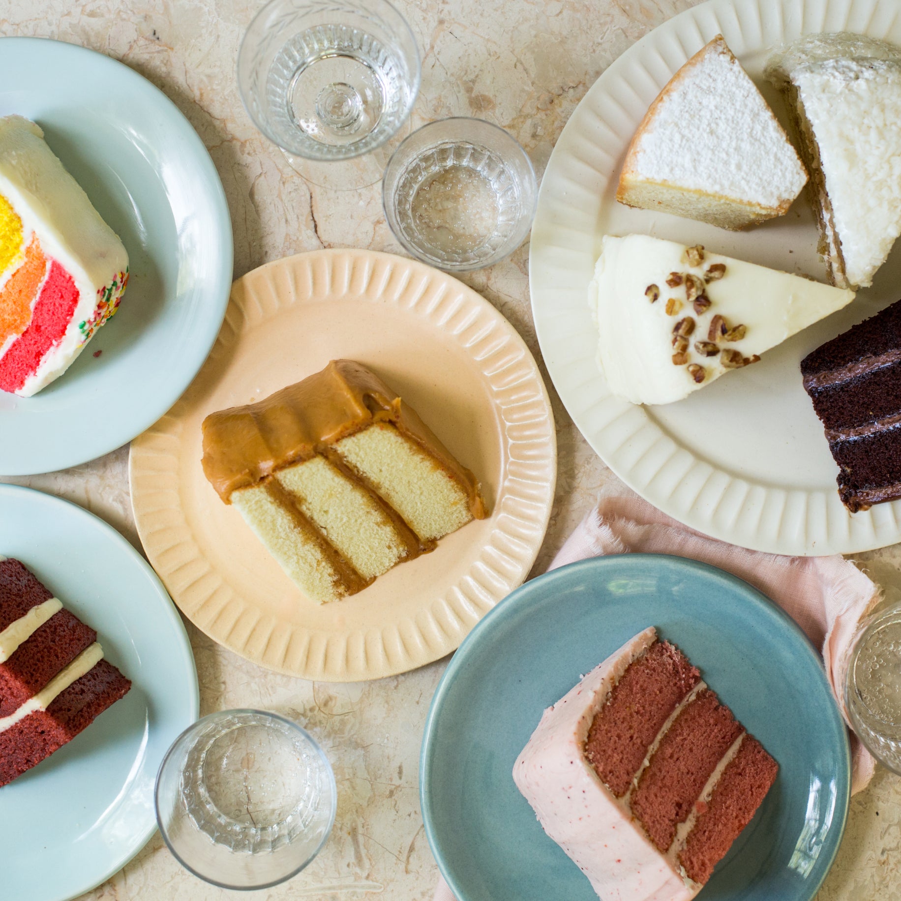 several varieties of cake, sliced and plated on a marble countertop