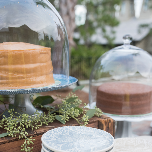 Various cakes in glass display amongst greenery
