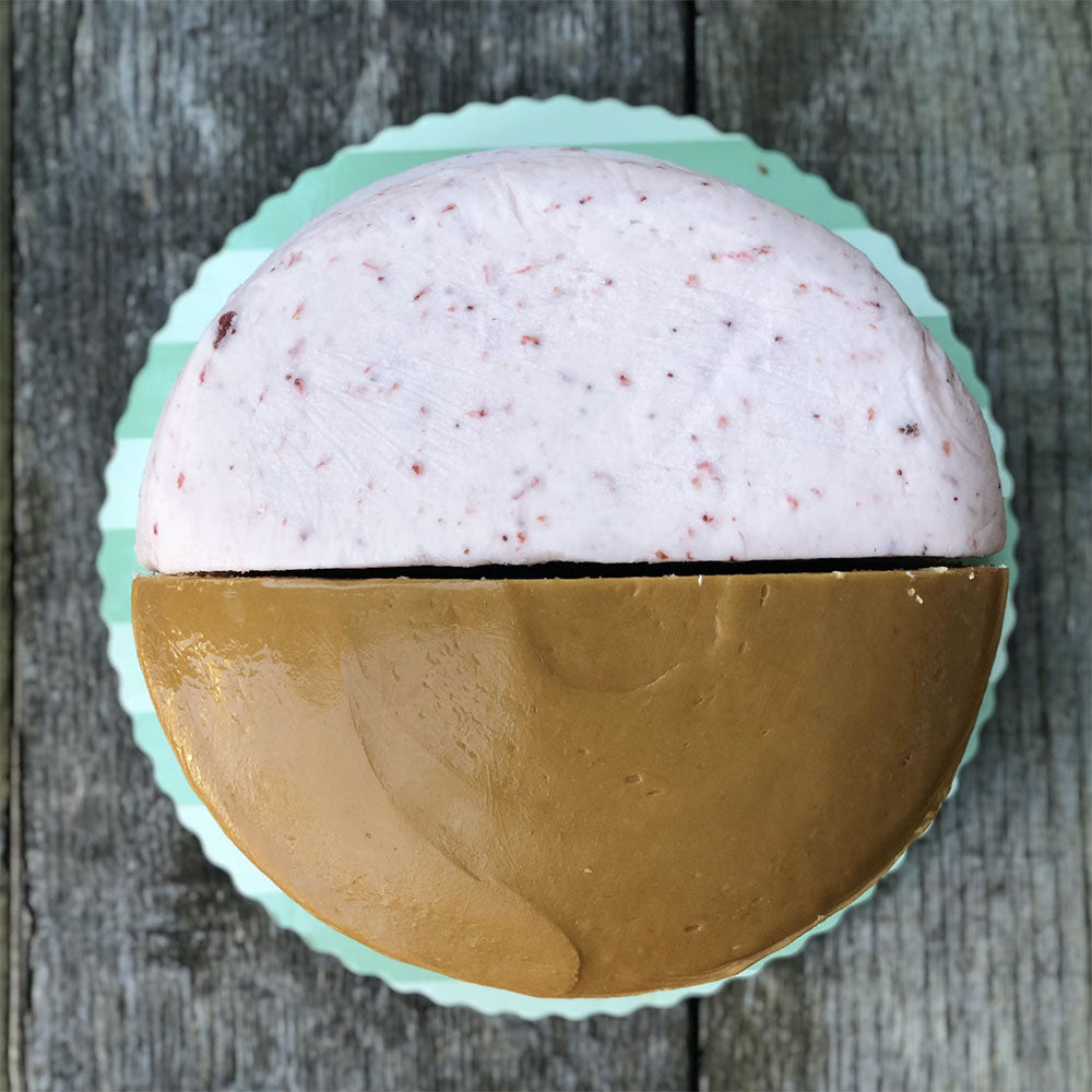 Half caramel and half strawberry cake on a wooden countertop