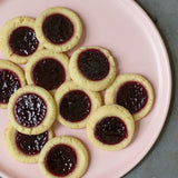 Blackberry tarts on a pink tray on top of a concrete countertop