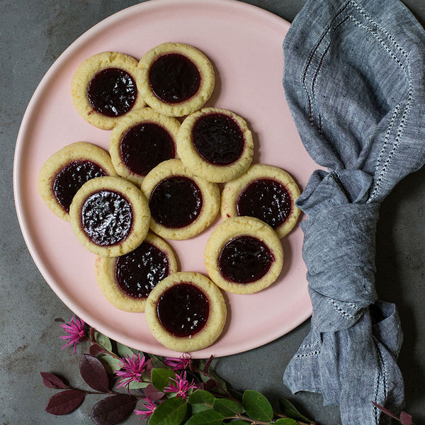 Blackberry tarts on a pink tray next to wildflowers and a cloth towel