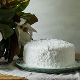 Coconut cake on an aqua colored plate next to a plant