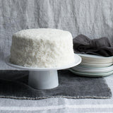 Whole coconut cake on a white tray with a gray background