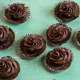 Unwrapped chocolate cupcakes on a teal countertop