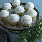 Coconut cupcakes on a metal tray next to white flowers
