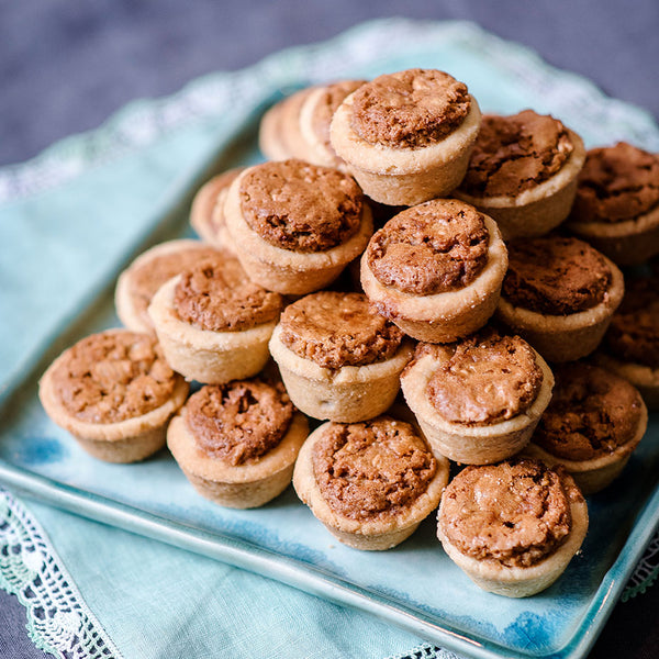 a plated pyramid of pecan tassies atop a blue cloth napkin
