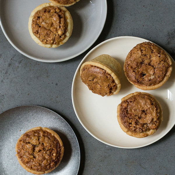 six pecan tassies plated on a grey countertop