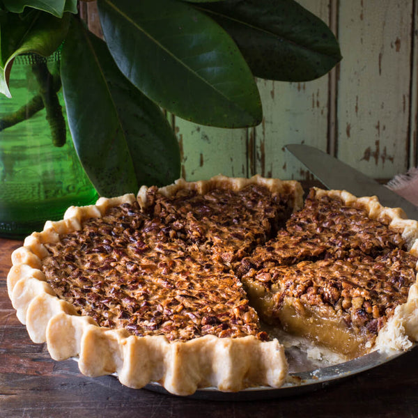 a pecan pie plated next to a plant with one slice missing
