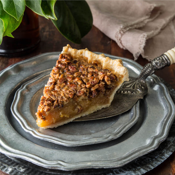 A slice of pecan pie with a vintage pie server on a silver plate