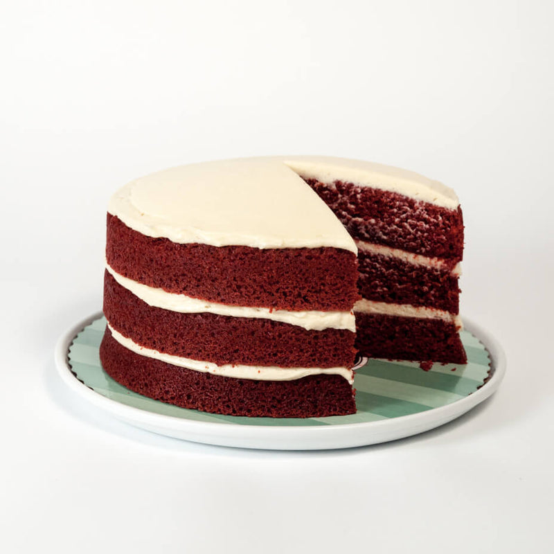 A red velvet cake with a slice missing on a white plate