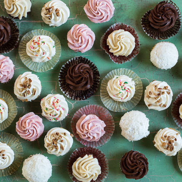 Various types of Sugaree's cupcakes on a green countertop