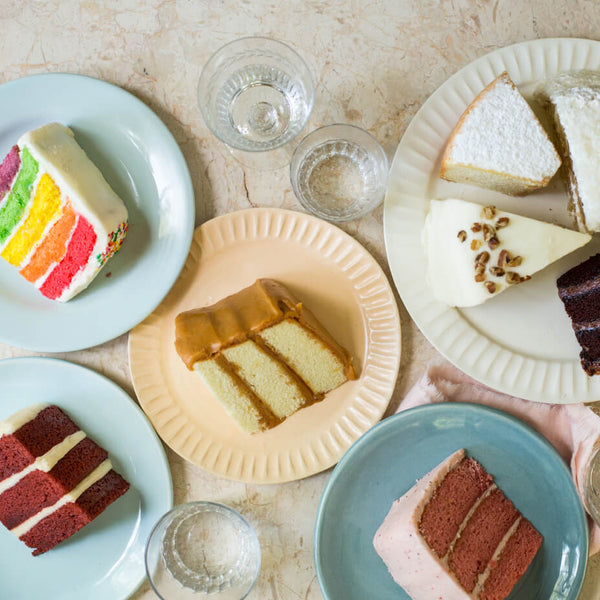 Chocolate, rainbow, Italian cream, strawberry, red velvet, cream cheese pound cake and Southern caramel cake slices on white, pink and teal plates