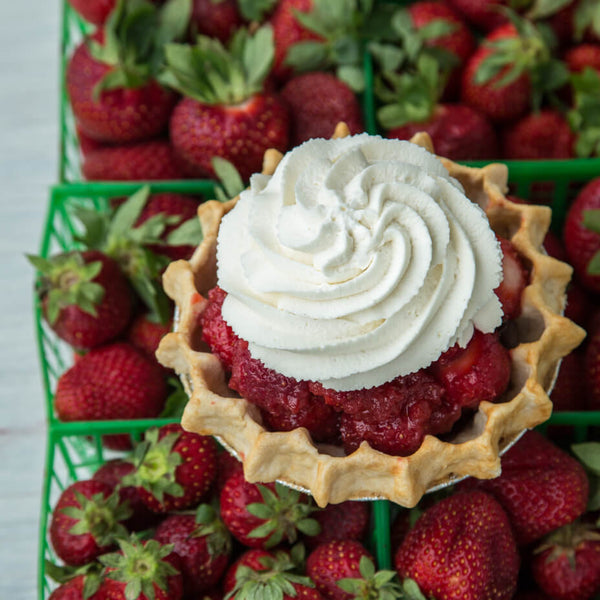 Small strawberry pie on top of containers of strawberries