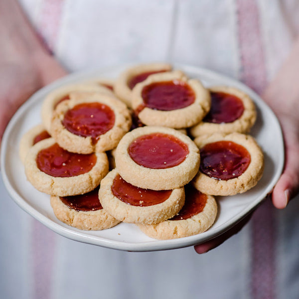 Person holding a plate of strawberry tarts