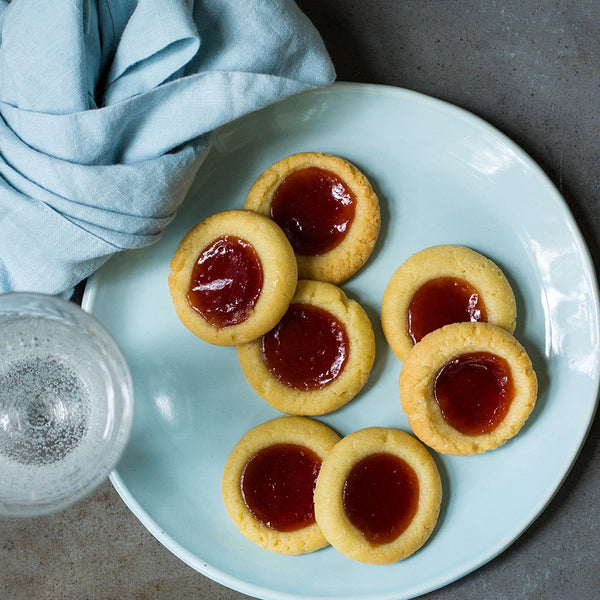 Strawberry tarts on a blue plate next to a blue tablecloth