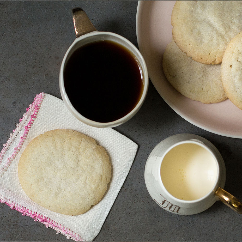 Tea cakes next to a cup of coffee and cream