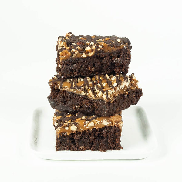 Stack of three turtle brownies on a white plate