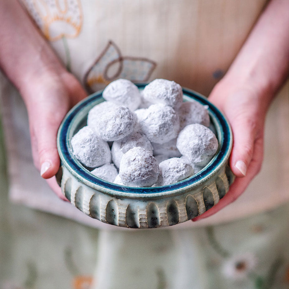 Person holding a bowl of wedding cookies