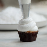 Coconut Cupcake being frosted with sky high marshmallowy icing using a piping bag