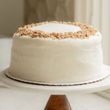 Sugaree’s Italian Cream Cake with white frosting and crumbly nut topping on a white plate