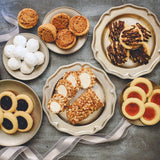 Assorted Sugaree’s cookies and tarts on decorative plates on a textured surface