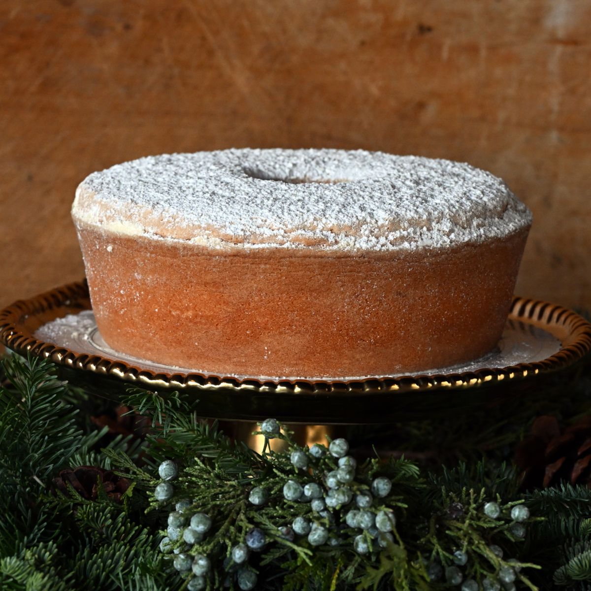 Sugaree’s Pound Cake dusted with powdered sugar on a wooden stand with a rustic background