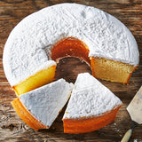 Sugaree’s Cream Cheese Pound Cake with white frosting on a wooden surface