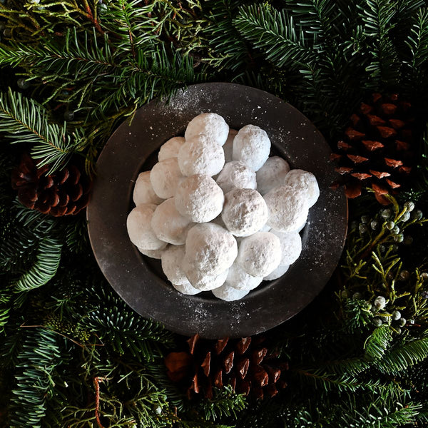Sugaree’s Wedding Cookies, sugar dusted in a bowl surrounded by greenery and pine cones