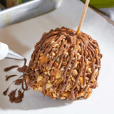 Sugaree’s Turtle Caramel Apple being piped with chocolate drizzle