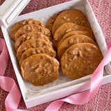 Valentine gift box with 12 Sugaree’s Pralines and a pink ribbon on a textured background