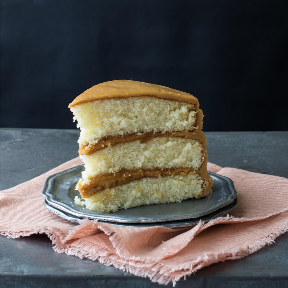 Slice of caramel cake on a concrete countertop