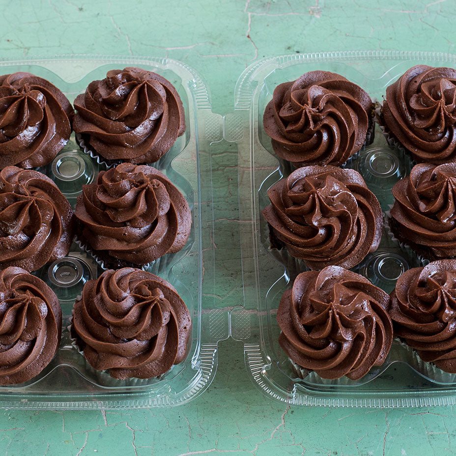 Two six packs of chocolate cupcakes on a teal countertop