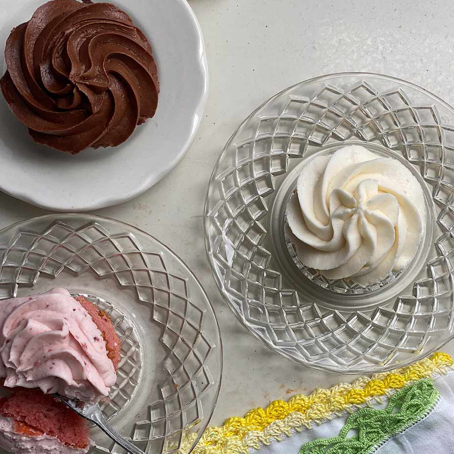 Chocolate, strawberry and vanilla cupcakes on glass and ceramic plates