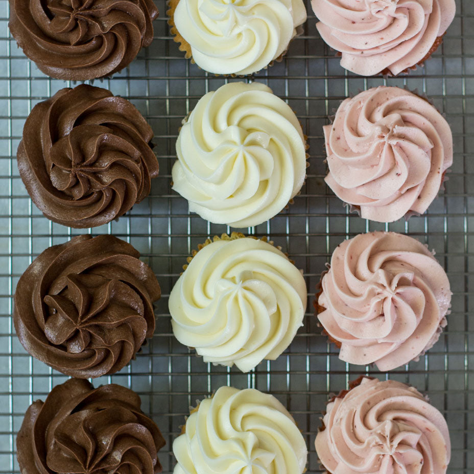 Chocolate, strawberry and vanilla cupcakes on cooling rack