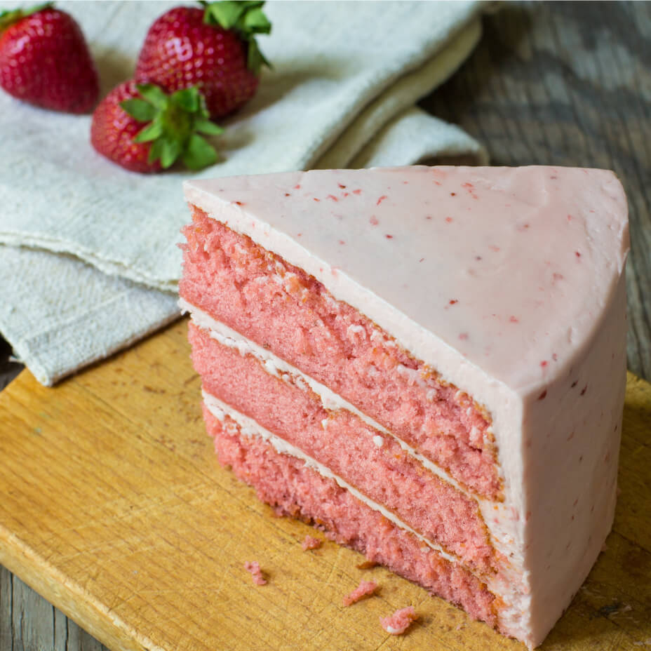 Slice of strawberry cake next to strawberries